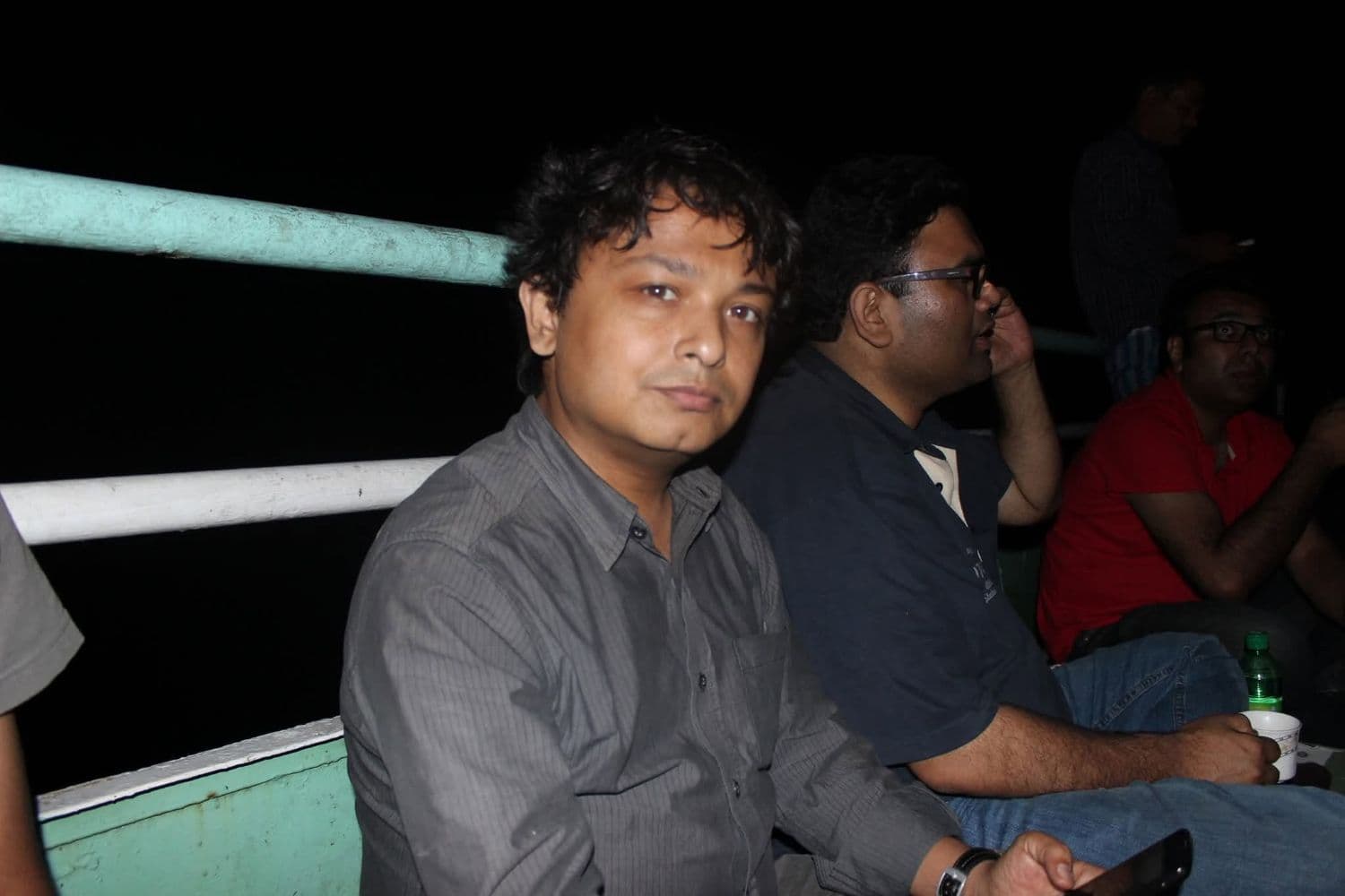 Dr. Sabbir seated on the deck of a boat at night, with colleagues