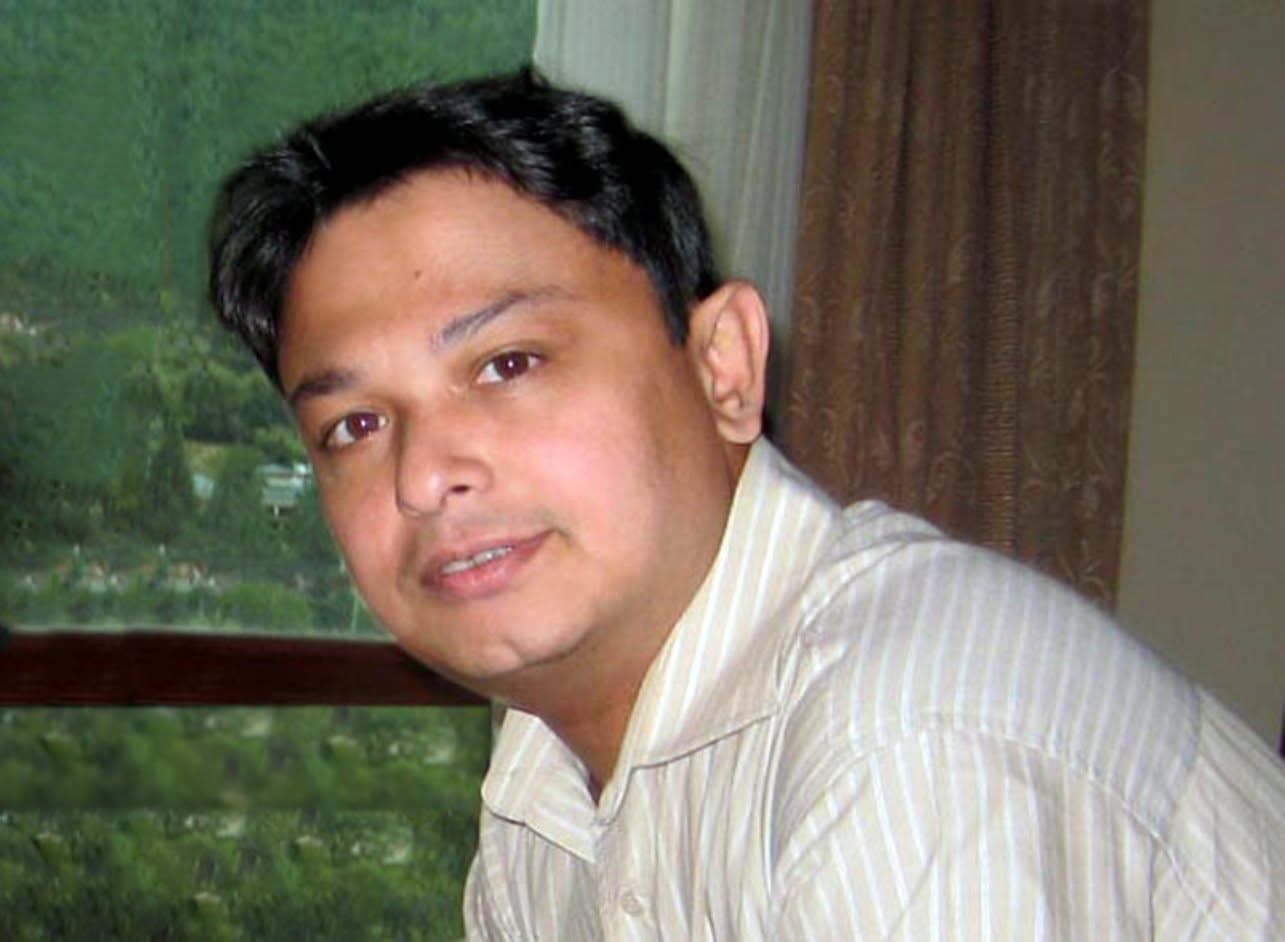 Dr. Sabbir smiling, beside a window looking out over green hills